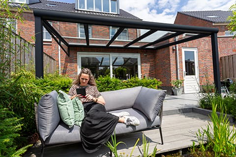 Ein Garten mit vielen Pflanzen und einer matt schwarzen Terrassenüberdachung